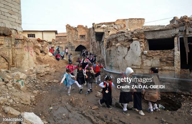 Iraqi students walk through a damaged road on their way back from school in the northern city of Mosul on November 28, 2018.