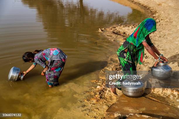 indian young girls collecting potable water from the lake, desert village, india - water well stock pictures, royalty-free photos & images