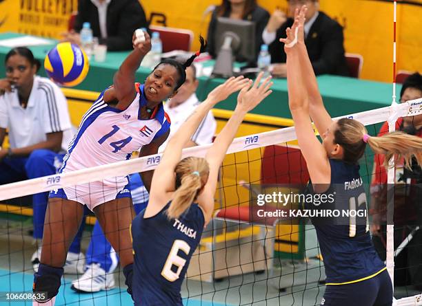 Cuba's Kenia Carcaces Opon spikes the ball over Brazil's Thaisa Menezes and Josefa Fabiola de Souza during their second round match at the World...