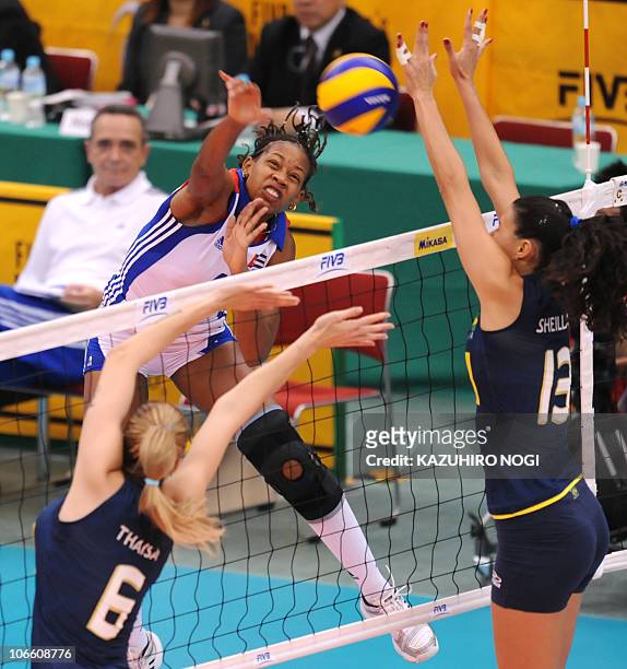 Cuba's Yoana Palacios Mendoza spikes the ball over Brazil's Thaisa Menezes and Sheilla Castro during their second round match at the World Women's...