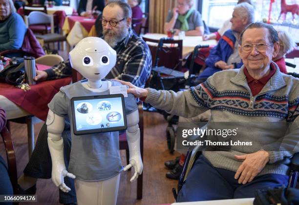 An elderly resident touchs a robot called "Pepper" during a presentation of two robots at the August-Stunz-Altenzentrum senior care facility on...