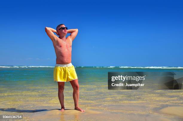 hombre joven disfruta del sol y la playa - hombre joven stock pictures, royalty-free photos & images