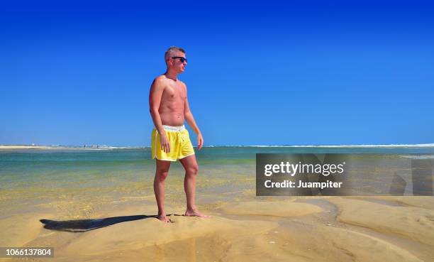 hombre joven disfruta del sol y la playa - hombre joven stock pictures, royalty-free photos & images