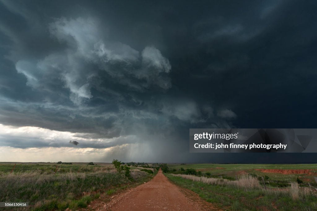 A red dirt road leads into a Tornado warned severe thunderstorm, Waynoka, Oklahoma. USA