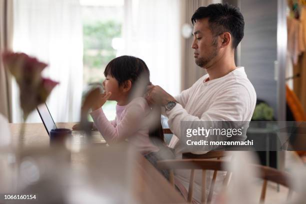 Father fixing daughter's hair at home