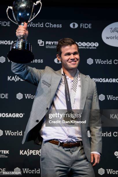 Norwegian Magnus Carlsen holds his winning trophy up after beating his opponent, American Fabiano Caruana to regain his World Chess Championship...