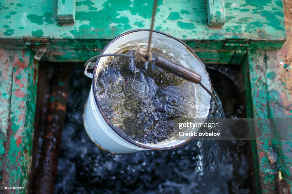 L’eau de pluie propre et claire dans un seau est déclenché dans un puits