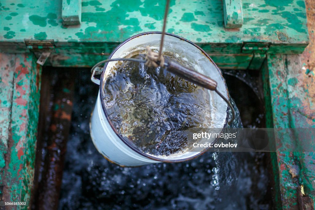 Schoon en helder regenwater in een emmer is uit een put opgewekt