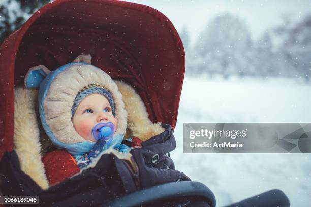 little boy in stroller in winter park - winter baby stock pictures, royalty-free photos & images
