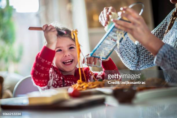 mother and daughter in the kitchen, eating spaghetti together - lunch cheese imagens e fotografias de stock