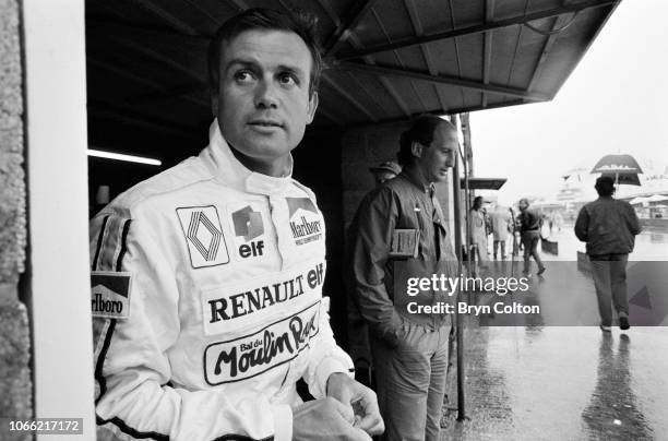 Formula One Grand Prix racing driver Patrick Tambay, driving for Renault, shelters from the rain whilst standing in his pit lane garage during a...