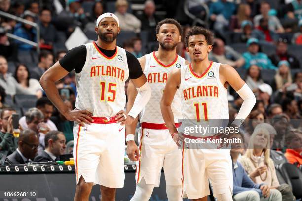 Vince Carter, Justin Anderson, and Trae Young of the Atlanta Hawks look on during the game against the Charlotte Hornets on November 28, 2018 at the...