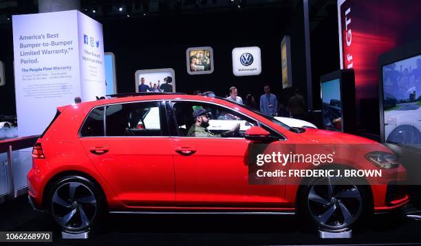 Man seats at the wheel of a new Volkswagen Golf GTI on display in Los Angeles, California on November 28, 2018 at Automobility LA, formerly the LA...