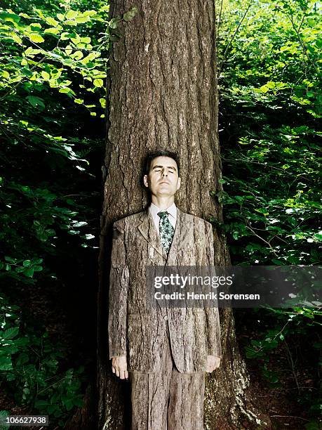 businessman wearing bark textured suit in woods - verbergen stockfoto's en -beelden