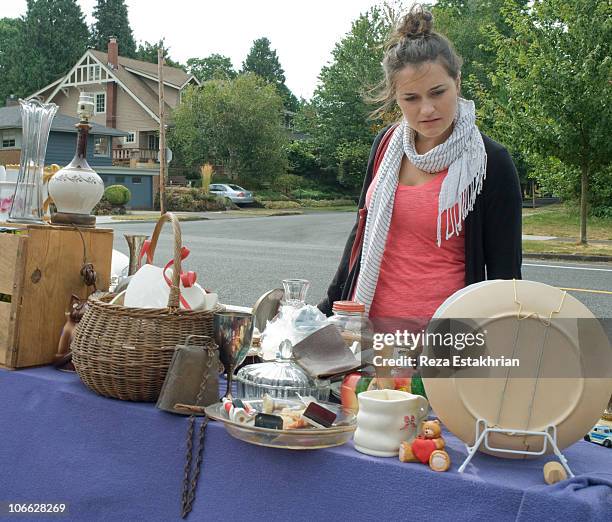 young girl checks products at yard sale - ガレージセール ストックフォトと画像