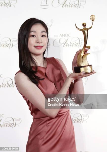 South Korea's Kim Yu Na, the 2010 Vancouver Olympic figure skating champion, holds her trophy for Outstanding Performance at the award ceremony of...
