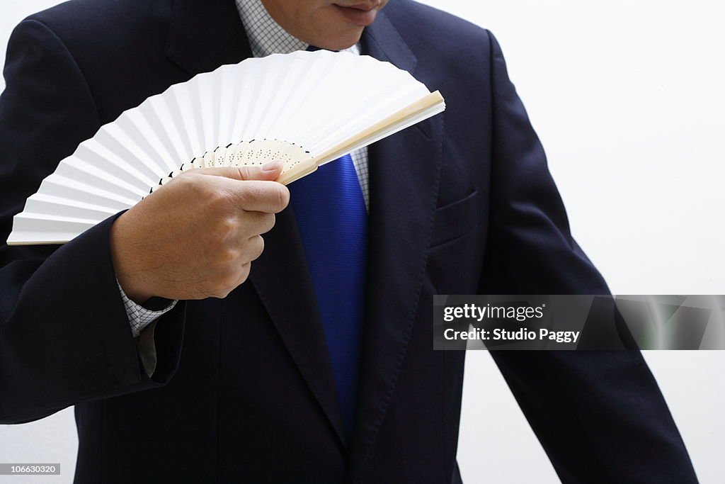 Close-up of a businessman holding a folding fan