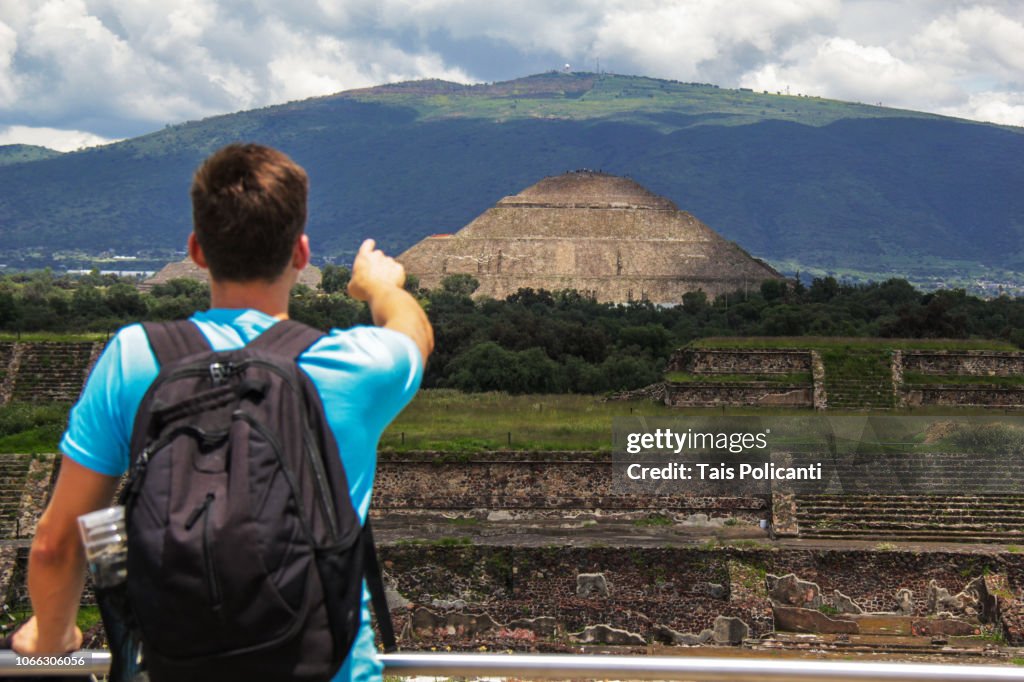 Man exploring and pointing at the Sun Pyramid in the ancient city of Teotihuacanm Mexico.