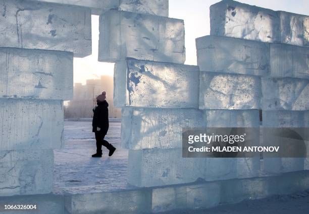 Woman walks behind an ice wall set up at the central square of the eastern Siberian town of Yakutsk with the air temperature at about minus 39...