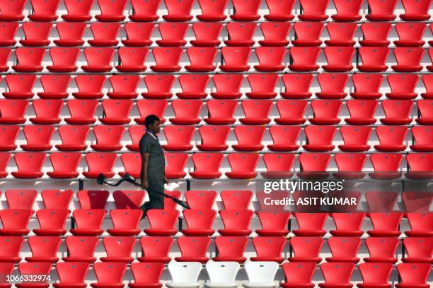 An Indian police official holding a detection device walks past empty stadium seating ahead of group stage matches between Argentina and Spain, to be...