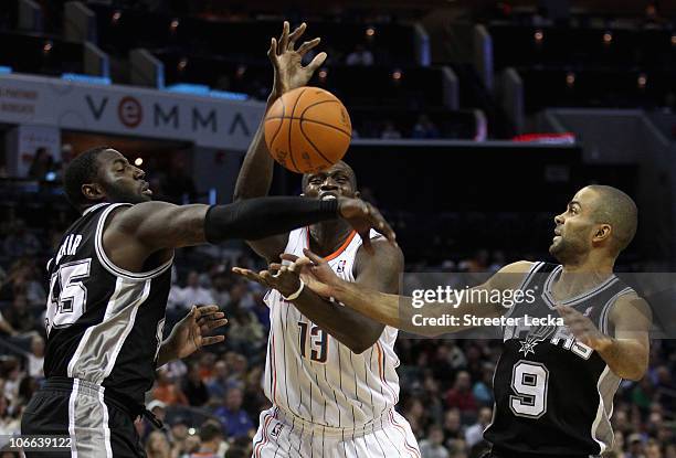 Teammates Tony Parker and DeJuan Blair of the San Antonio Spurs battle for a loose ball with Nazr Mohammed of the Charlotte Bobcats during their game...