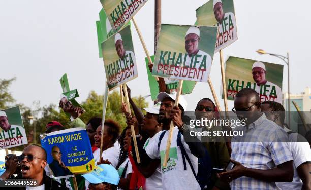 Senegal's opposition demonstrators hold pictures of former minister Karim Wade and of the Mayor of Dakar Khalifa Sall during a march to demand...