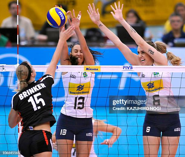 Brazil's Sheilla Castro and Thaisa Menezes try to block a spike by Germany's Maren Brinker during their second round match of the world women's...