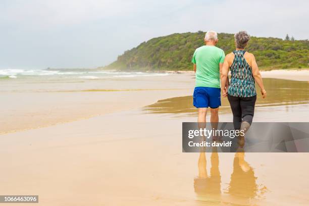 senior couple walking together on the beach - australasia stock pictures, royalty-free photos & images