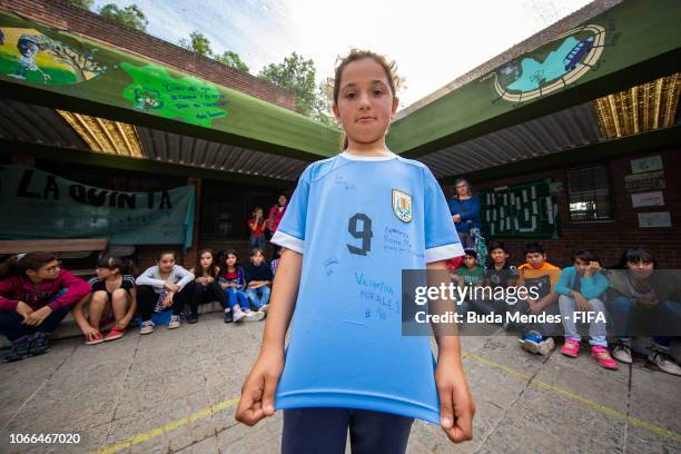 Student poses for a photo with her autographed jersey by the players of the Uruguay team during a meeting at Escola 355 during the FIFA U-17 Women's...