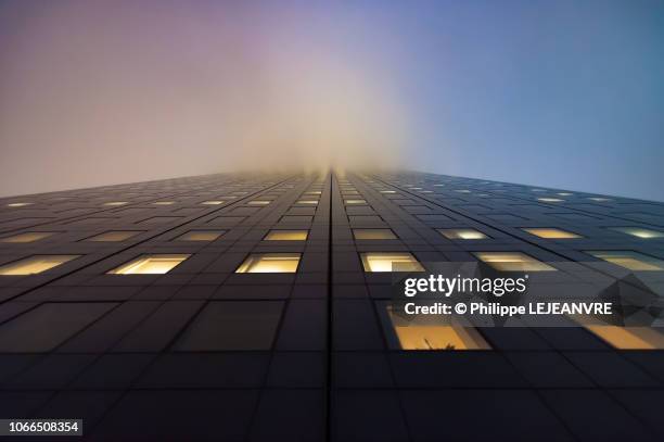 illuminated skyscraper in the fog against sky at night - altas luces fotografías e imágenes de stock