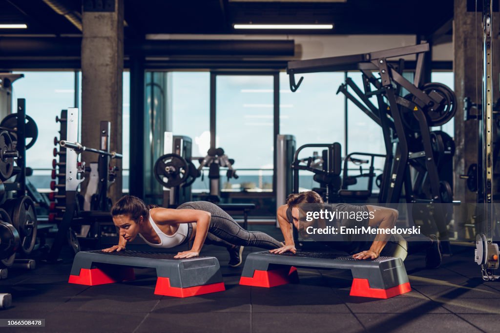 Two people doing push-ups on the step aerobics equipment