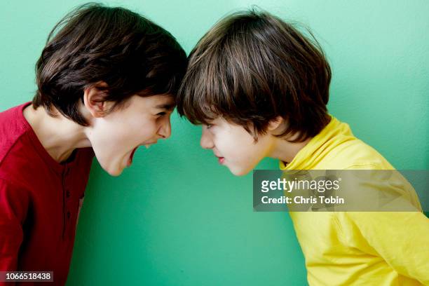 two young boys screaming and fighting and clashing violently - diverbio foto e immagini stock