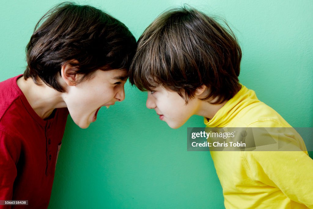 Two young boys screaming and fighting and clashing violently