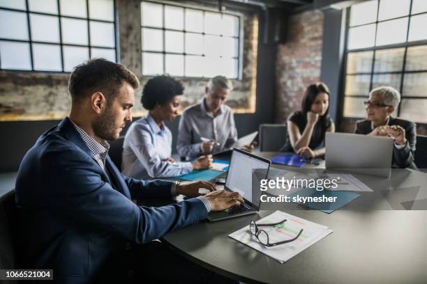 vista de perfil de un hombre de negocios utilizando la computadora portátil en una reunión en la oficina. - five people fotografías e imágenes de stock