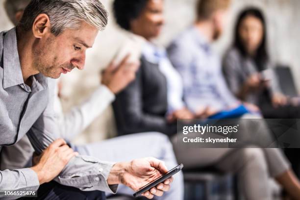 mid adult businessman using mobile phone while waiting for a job interview. - job search stock pictures, royalty-free photos & images