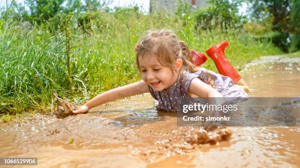 mädchen spielen im schlammigen wasser - girls in wet dresses stock-fotos und bilder