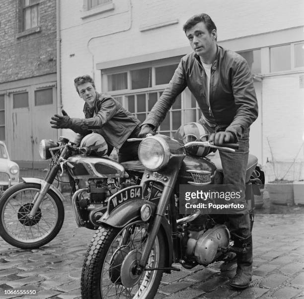 View of two motorcyclists wearing leathers seated on their motorbikes, including a Triumph Thunderbird on right, parked on a mews street in London in...