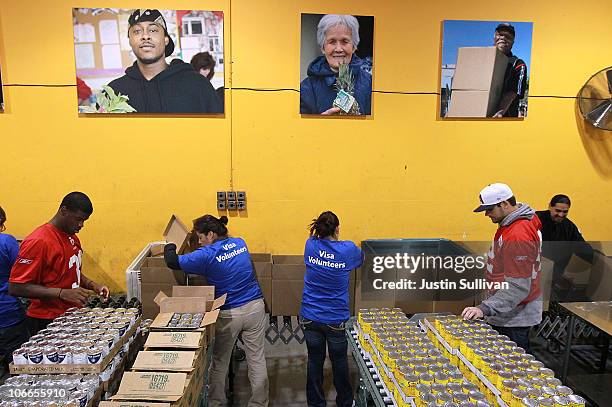 Reggie Smith and Nate Byham of the San Francisco 49ers pack boxes of food while volunteering at the San Francisco Food Bank on November 9, 2010 in...