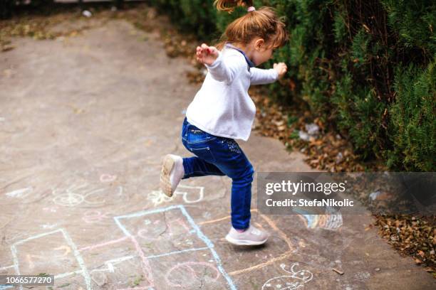 aktives kleines mädchen genießt hopscotch spielen - hopscotch stock-fotos und bilder