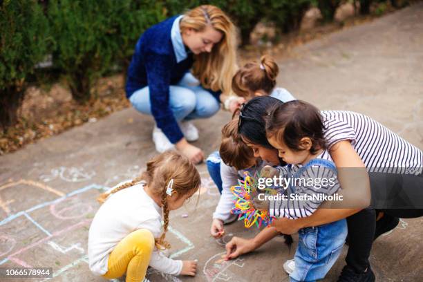 girls drawing hopscotch - family garden play area stock pictures, royalty-free photos & images