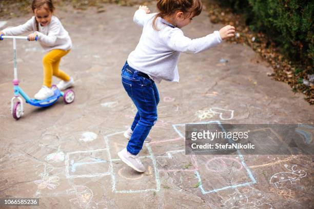 little girls play hopscotch on playground - hopscotch stock pictures, royalty-free photos & images