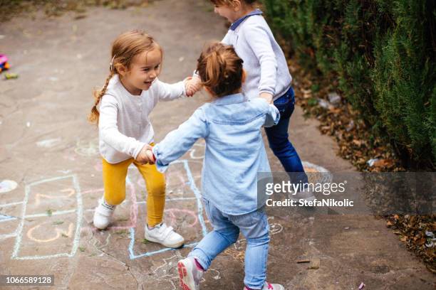 amigos de niño jugando rayuela al aire libre - tres amigos fotografías e imágenes de stock
