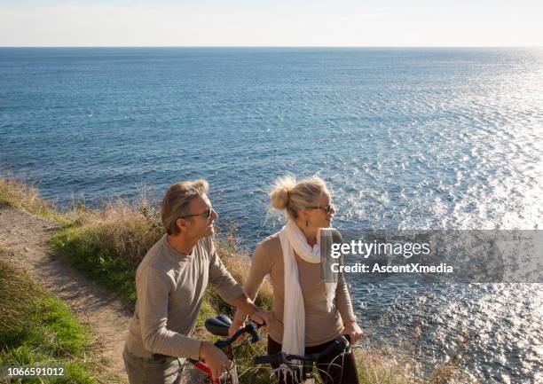 couple walk with bicycle above the sea - woman finding grey hair stock pictures, royalty-free photos & images