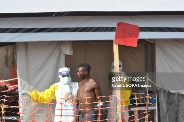 Health workers seen helping an Ebola patient outside an isolation tent at the Ebola treatment center. Ebola treatment center in Beni, eastern...