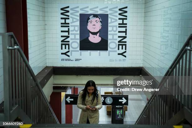 Poster advertisement for The Whitney Museum's new Andy Warhol retrospective hangs on the wall as a commuter walks through the 14th Street/Eighth...