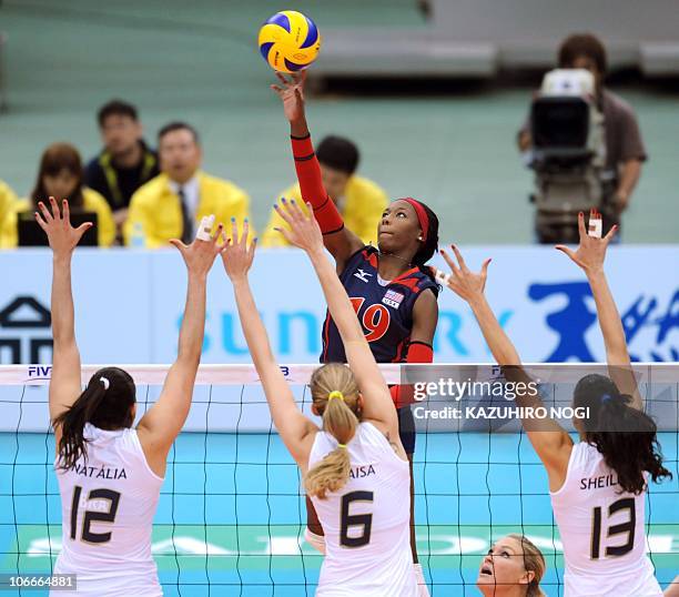 Attacker Destinee Hooker tries to spike over Brazilian players Natalia Pereira , Thaisa Menezes and Sheilla Castro during their second round match of...