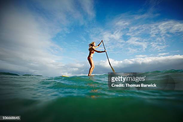 female stand up paddle boarder paddling on ocean - sup stockfoto's en -beelden