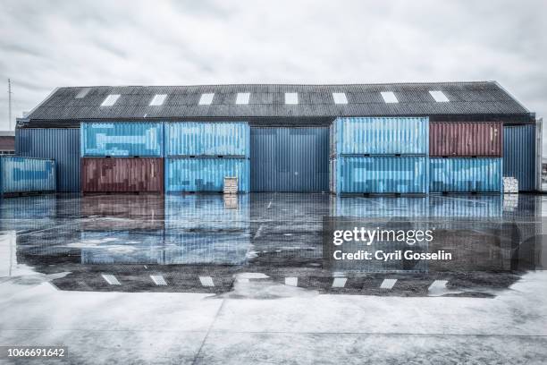reflected warehouses on a rainy day - entsättigt stock-fotos und bilder