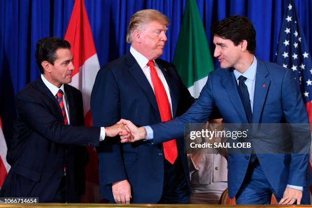 Mexico's President Enrique Pena Nieto shakes hands with Canadian Prime Minister Justin Trudeau next to US President Donald Trump after signing a new...