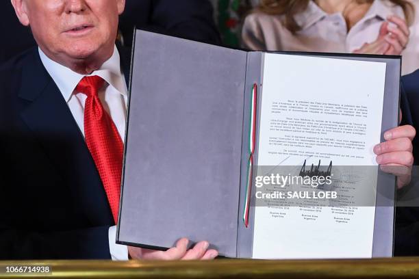 President Donald Trump shows a document after signing a new free trade agreement with Mexico's President Enrique Pena Nieto and Canadian Prime...